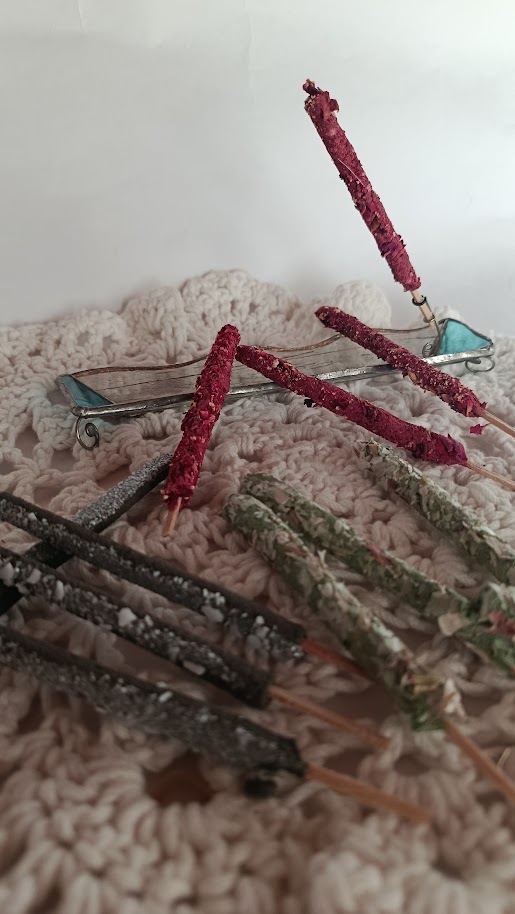 Sahumerios naturales en varillas, rojizos y oscuros, sobre un tejido al crochet