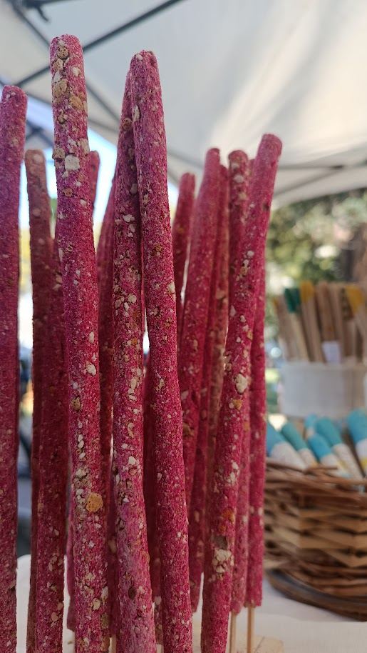 Sahumerios naturales en varillas de color rojizo y rosado, cubiertos de pétalos